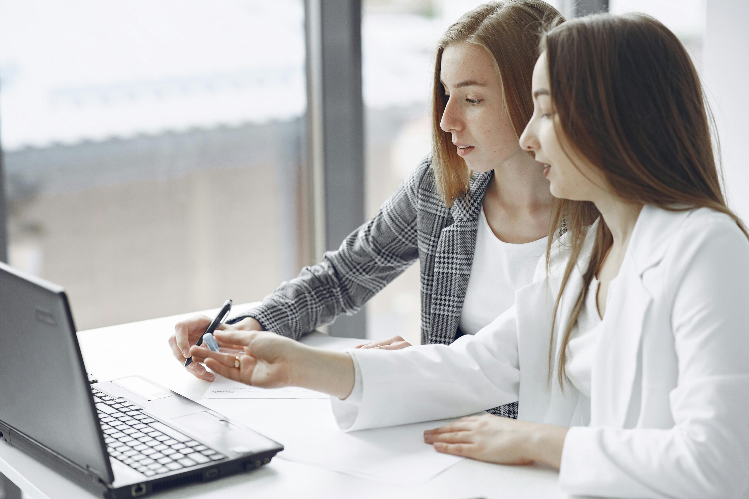 Two professional women engaged in a collaborative work session in a bright modern office.
